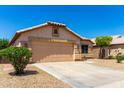 Single-story home with a tan stucco exterior, two-car garage, desert landscaping, and a tidy lawn at 10934 W Almeria Rd, Avondale, AZ 85392