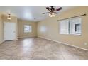 Spacious living room features tile floors, ceiling fan, and two windows at 15955 N Cristine Ln, Surprise, AZ 85388