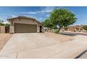 Well-maintained one-story home features desert landscaping, a tile roof, and a spacious concrete driveway to the two-car garage at 17828 W Calavar Rd, Surprise, AZ 85388