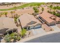 Aerial view of a home showing a three car garage and landscaping, with a desert golf course in the background at 22625 N Van Loo Dr, Maricopa, AZ 85138
