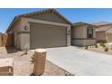 A single-story home featuring a two-car garage, neutral color palette, and desert landscaping at 22913 N 183Rd Dr, Surprise, AZ 85387