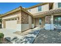 Home featuring a two-car garage, stone accents, a walkway to the front door and a well-manicured front yard at 29828 N 72Nd Ln, Peoria, AZ 85383