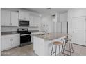 Kitchen with white cabinets, granite counters, a stainless steel microwave, and a center island with seating at 36987 N Sidewinder Dr, San Tan Valley, AZ 85140