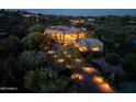 Aerial view showcasing the beautifully landscaped property and the surrounding desert landscape with illuminated driveway at 41667 N 113Th Pl, Scottsdale, AZ 85262