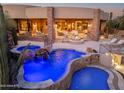 Backyard featuring a blue-lit pool, spa with a waterfall, and an outdoor living area with a cozy fire pit at 41667 N 113Th Pl, Scottsdale, AZ 85262