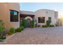 Exterior view of house with arched entry, desert landscaping, and paver driveway at 41667 N 113Th Pl, Scottsdale, AZ 85262
