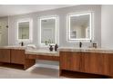 Bright bathroom featuring double sinks, wood cabinets and large lighted mirrors at 4532 E Sandra Ter, Phoenix, AZ 85032