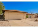 Attached two-car garage with a paved driveway and desert landscaping surrounding the home at 4957 W Onyx Ave, Glendale, AZ 85302