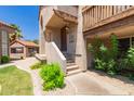 Close-up of the entryway with stucco stairs, a wooden door, and vibrant green bushes at 700 E Mesquite Cir # O210, Tempe, AZ 85288