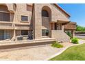 View of the exterior featuring textured stucco, a red terracotta roof, and lush green landscaping at 700 E Mesquite Cir # O210, Tempe, AZ 85288