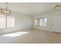Bright, airy living room with neutral tile flooring, large windows, and modern light fixtures for a welcoming atmosphere at 9939 W Southgate Ave, Tolleson, AZ 85353