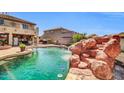 Backyard pool showcases a stunning rock waterfall feature, adding a natural and luxurious element to the outdoor space at 11965 W Monte Vista Rd, Avondale, AZ 85392