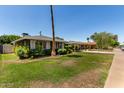 Well-maintained front yard with lush lawn, mature trees, and a charming single-story home at 1209 W Colter St, Phoenix, AZ 85013