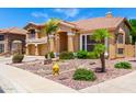 Charming two-story home featuring desert landscaping, mature palm trees, and a welcoming front entrance at 13324 W Annika Dr, Litchfield Park, AZ 85340