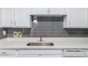 Modern kitchen with white cabinets, quartz countertops, and a gray subway tile backsplash at 15610 N 29Th St # 3, Phoenix, AZ 85032