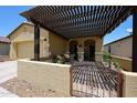 An exterior shot of a charming covered front porch featuring a metal gate and desert landscaping at 17516 W Glenhaven Dr, Goodyear, AZ 85338