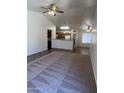 Spacious open living room with carpet, ceiling fan, and view to kitchen and dining area at 13004 W Saint Moritz Ln, El Mirage, AZ 85335