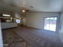 Carpeted living room with open floorplan looking towards a kitchen and sliding glass door at 13004 W Saint Moritz Ln, El Mirage, AZ 85335