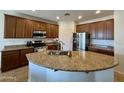A kitchen features granite countertops and an island sink with wood cabinets at 16559 W Lincoln St, Goodyear, AZ 85338