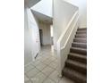 Hallway with neutral tiles and a staircase adjacent the entry, leading to the upper level of the home at 29906 W Whitton Ave, Buckeye, AZ 85396
