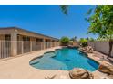 An inviting backyard pool with a rock waterfall feature and a secure fence at 3173 E Canyon Way, Chandler, AZ 85249