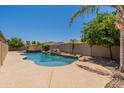 A spacious backyard featuring a private pool with a rock waterfall feature surrounded by lush greenery at 3173 E Canyon Way, Chandler, AZ 85249