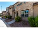 Charming townhome exterior featuring a mix of stone and stucco, complemented by lush landscaping and a private entrance at 4548 S Renaissance Dr # 103, Gilbert, AZ 85297