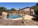 Private backyard featuring a sparkling pool, rock waterfall feature, and desert landscaping at 7327 W Donner Dr, Laveen, AZ 85339