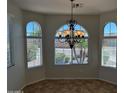 Elegant dining area enhanced by tile flooring, an ornate chandelier, and arched windows at 7327 W Donner Dr, Laveen, AZ 85339