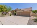 Attractive single-story home featuring a two-car garage, desert landscaping, and a tile roof at 10794 S Coolwater Dr, Goodyear, AZ 85338