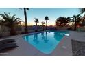 Backyard pool with palm trees, waterfall feature, and basketball hoop for outdoor entertainment at 10794 S Coolwater Dr, Goodyear, AZ 85338