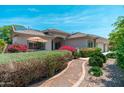 Beautiful exterior elevation with colorful shrubbery, an umbrella-covered patio, and solar panels on the roof at 13034 W Krall Ct, Glendale, AZ 85307