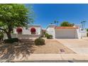 Inviting single-story home with stucco facade, red awnings, a two car garage, and desert landscaping at 38 E Calavar Rd, Phoenix, AZ 85022