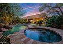 Backyard pool featuring a spa, lush landscaping, and ambient lighting perfect for outdoor entertaining and relaxation at 14598 E Corrine Dr, Scottsdale, AZ 85259