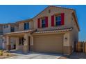 Charming two-story home featuring a two-car garage, red shutters, and desert landscaping at 18351 W Patrick Ln, Surprise, AZ 85387