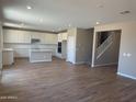 Spacious living room with wood-look tile, a staircase, recessed lighting, and a view of the modern kitchen at 18351 W Patrick Ln, Surprise, AZ 85387