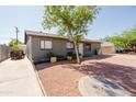 Home featuring gravel front yard and mature tree for shade in the desert landscape at 5637 N 63Rd Dr, Glendale, AZ 85301