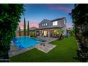 Beautiful backyard featuring a refreshing pool, lush lawn, covered patio, and palm trees, perfect for outdoor living at 7939 W Fetlock Trl, Peoria, AZ 85383