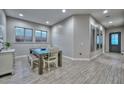 Bright dining room with wood-look tile flooring, a modern table set, and abundant natural light from large windows at 13162 W Golden Puma Trl, Peoria, AZ 85383