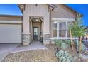 Charming entryway with a covered porch, stone columns, and desert landscaping creating curb appeal at 13162 W Golden Puma Trl, Peoria, AZ 85383