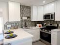 Modern kitchen featuring sleek stainless steel appliances, stylish tile backsplash, and white cabinets at 1561 N Sterling St, Mesa, AZ 85207