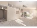 Bright living room with neutral carpet, fan, and sliding door access to the backyard at 16209 W Acapulco Cir, Surprise, AZ 85379
