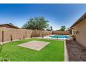 Landscaped backyard featuring a refreshing pool, artificial grass, and a brick patio at 308 W Oraibi Dr, Phoenix, AZ 85027