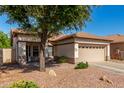 Single-story tan home with a two car garage, and low-maintenance desert landscaping at 3685 N 141St Dr, Goodyear, AZ 85395
