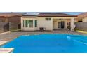 Sparkling pool with solar panels, landscaped backyard, and covered patio at 3685 N 141St Dr, Goodyear, AZ 85395