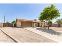 Single-story home with a two-car garage and driveway, partially xeriscaped front yard, and tidy landscaping at 4712 W Juniper Ave, Glendale, AZ 85306