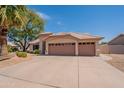 Single-story home with three-car garage, desert landscaping, and a private entryway at 7345 E Forge Ave, Mesa, AZ 85208