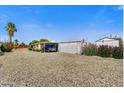 Spacious home featuring covered parking, low-maintenance gravel landscaping, and vibrant flowering bushes at 7711 E Farmdale Ave, Mesa, AZ 85208