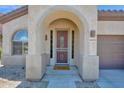 Charming front entrance with arched doorway, security door, and a 'HELLO' welcome mat at 18455 W San Carlos Dr, Goodyear, AZ 85338
