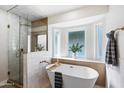 Serene bathroom featuring a freestanding tub, glass shower, and natural light from a window at 3220 W Frankfurt Dr, Chandler, AZ 85226